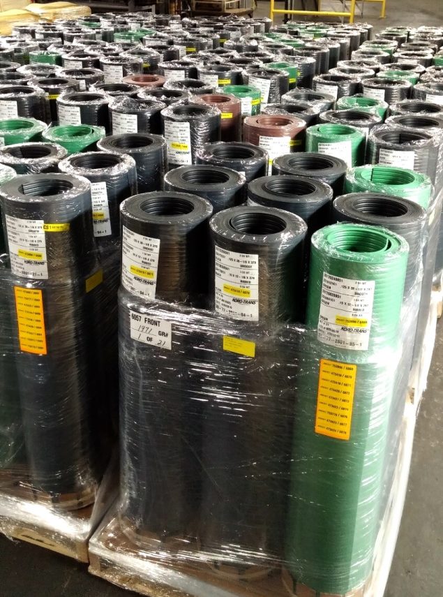 Pallets of rolled rubber material wrapped in plastic in a warehouse