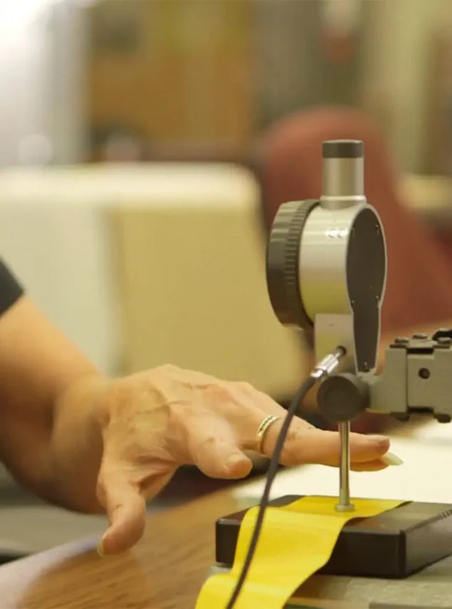 A person's hand rests near a dial indicator gauge on a stand